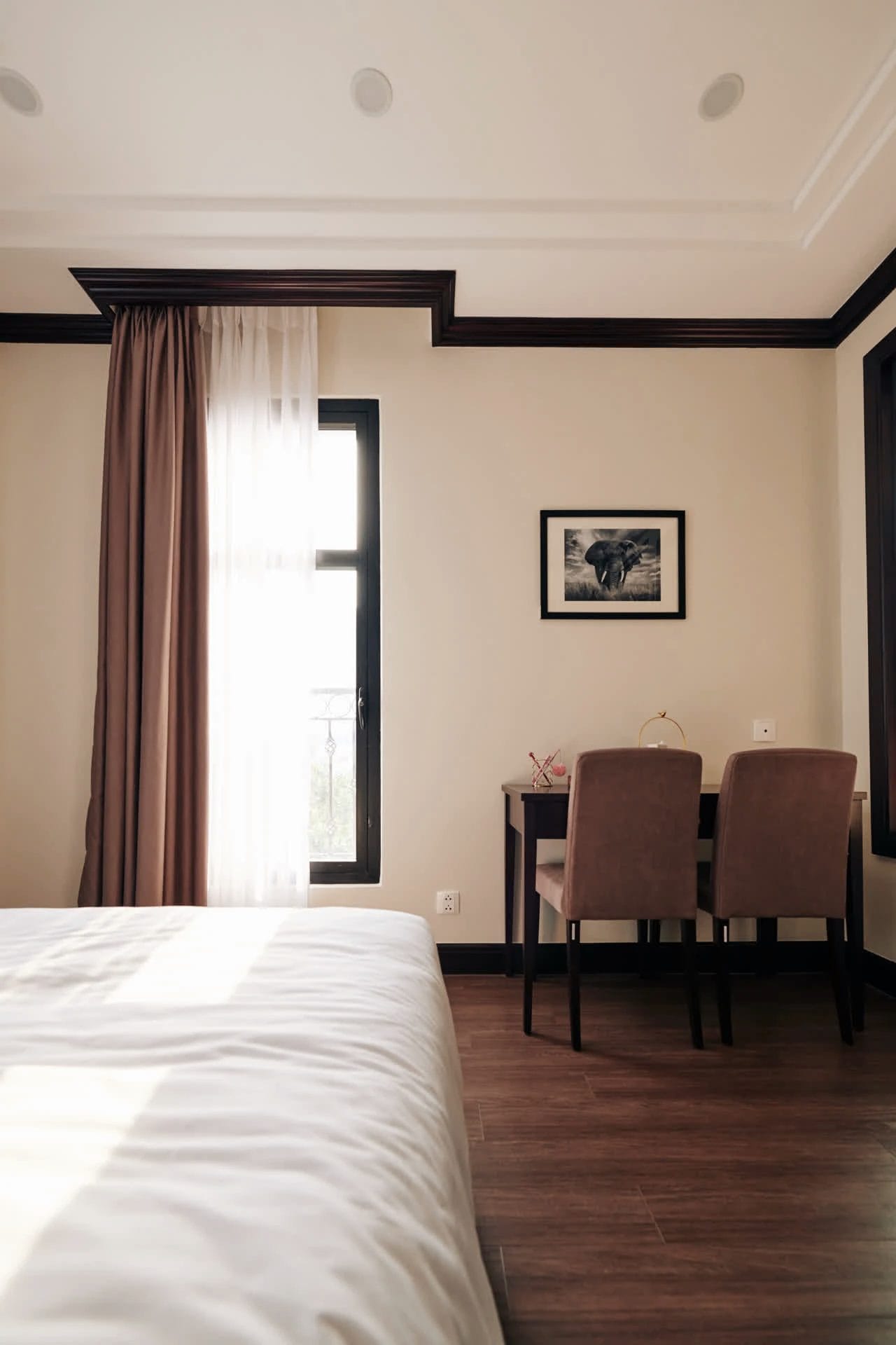 A room with a bed and a narrow window with made-to-measure curtains