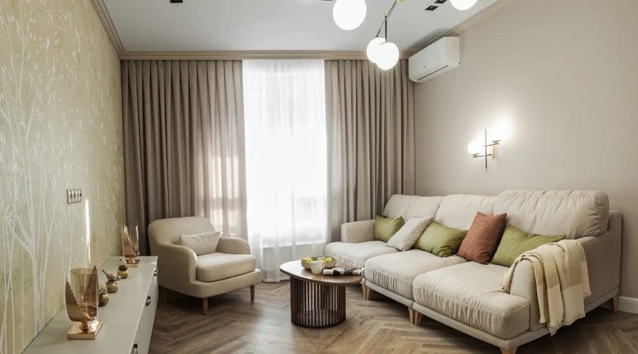 An arm chair and sofa sat in front of a bay window with made-to-measure curtains